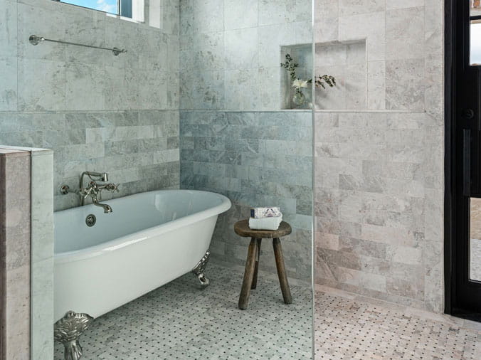 Claw foot bathtub in bathroom with grey tile walls