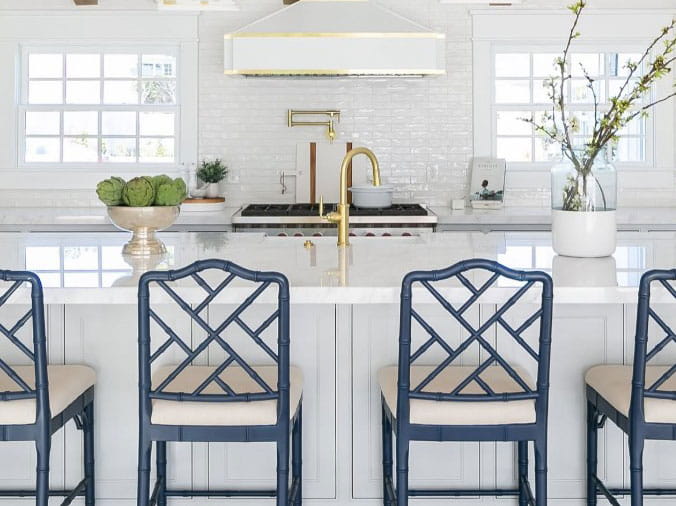 White kitchen with blue chairs and brass sink faucet
