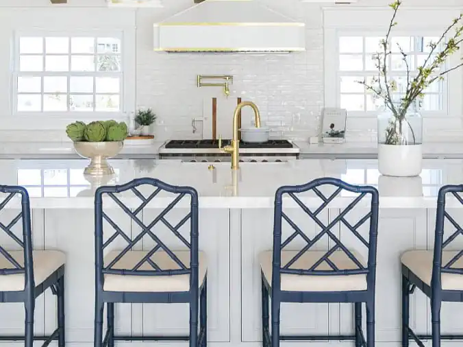 White kitchen with blue chairs and brass sink faucet