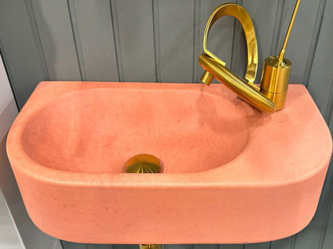 Small pink wall sink with brass faucet